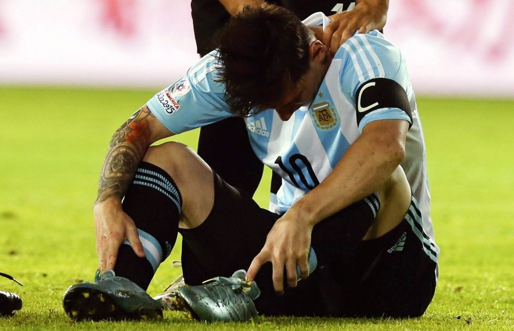 epa04798280 Argentina's Lionel Messi sits injured on the field next to teammate Sergio Aguero during the Copa America 2015 Group B soccer match between Argentina and Paraguay, at Estadio La Portada de La Serena in La Serena, Chile, 13 June 2015. EPA/Juan Carlos Cardenas