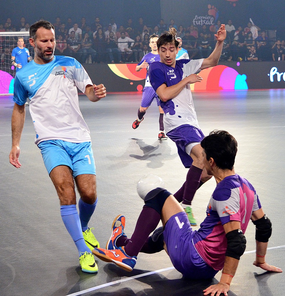 Former Manchester United footballer Ryan Giggs (L) is tackled while taking part in the final of the Indian Premier Futsal Football League match at The Peddem Indoor Stadium in Mapusa on July 24, 2016. / AFP / STR (Photo credit should read STR/AFP/Getty Images)