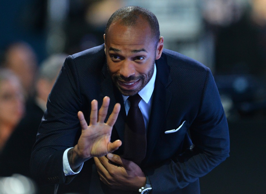 Former French international Thierry Henry waves during a men's singles semi-final match between Switzerland's Roger Federer and Switzerland's Stan Wawrinka on day seven of the ATP World Tour Finals tennis tournament in London on November 21, 2015. / AFP / GLYN KIRK (Photo credit should read GLYN KIRK/AFP/Getty Images)