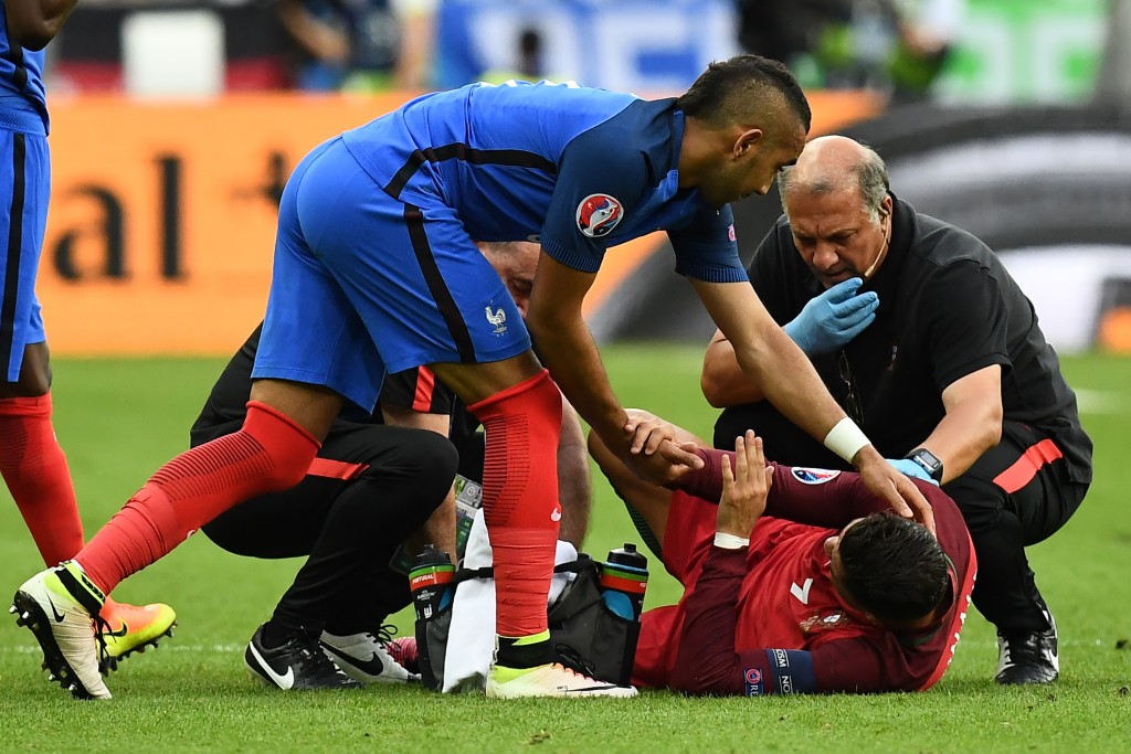 TOPSHOT - France's forward Dimitri Payet holds the hand of Portugal's forward Cristiano Ronaldo as he lies on the pitch during the Euro 2016 final football match between France and Portugal at the Stade de France in Saint-Denis, north of Paris, on July 10, 2016. / AFP / FRANCK FIFE (Photo credit should read FRANCK FIFE/AFP/Getty Images)