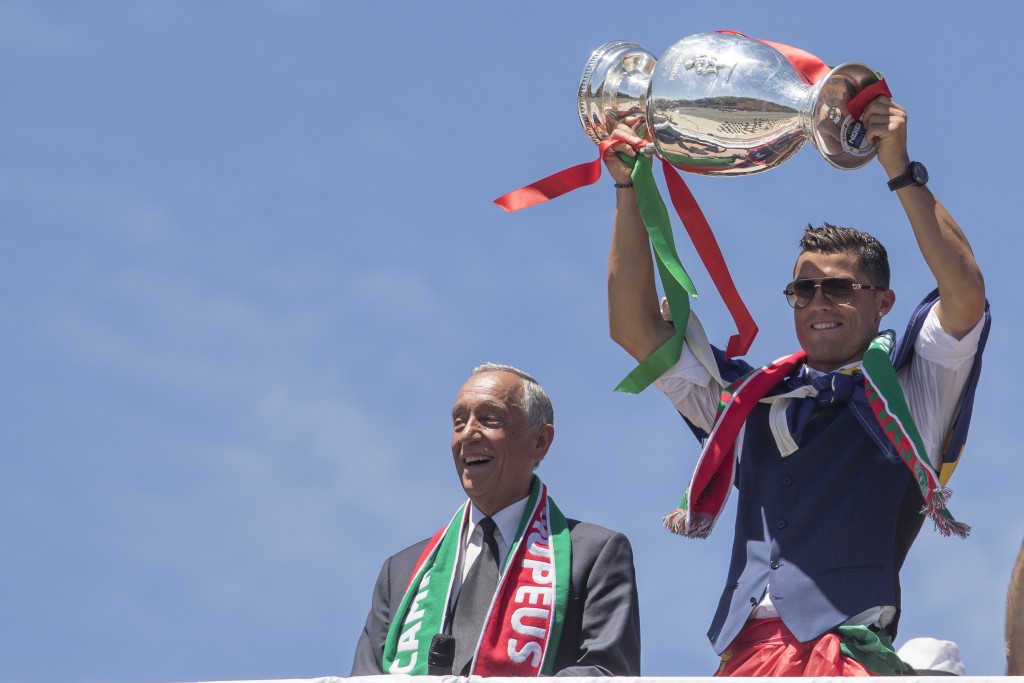 LISBON, PORTUGAL - JULY 11: Portuguese forward Cristiano Ronaldo (R) and Portuguese President Marcelo Rebelo de Sousa (L) showing the European cup to the supporters during the meeting with the Portuguese President Marcelo Rebelo de Sousa for the Portugal Euro 2016 Victory ceremonies at Lisbon on July 11, 2016 in Lisbon, Portugal. (Photo by Carlos Rodrigues/Getty Images)
