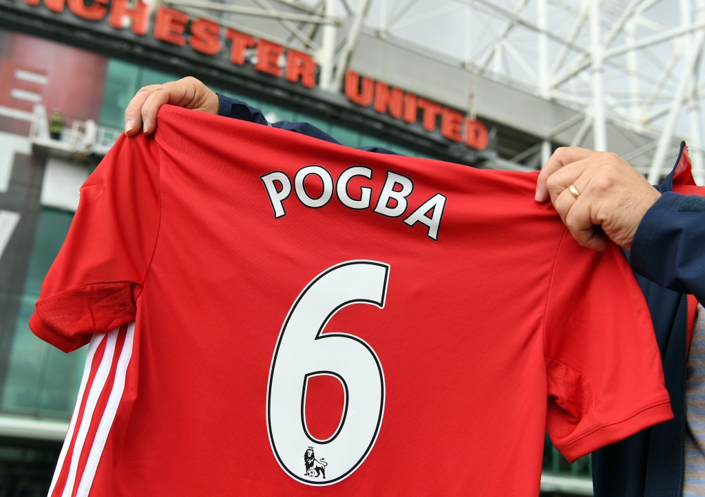A man poses for pictures after purchasing a Manchester United shirt with the name and squad number of recent signing French midfielder Paul Pogba outside Old Traford in Manchester, north west England, on August 9, 2016. The world record for a transfer fee was shredded Tuesday when French superstar Paul Pogba completed a sensational return to Manchester United from Juventus for 105 million euros ($116 million) (Photo by Paul Ellis/AFP/Getty Images)