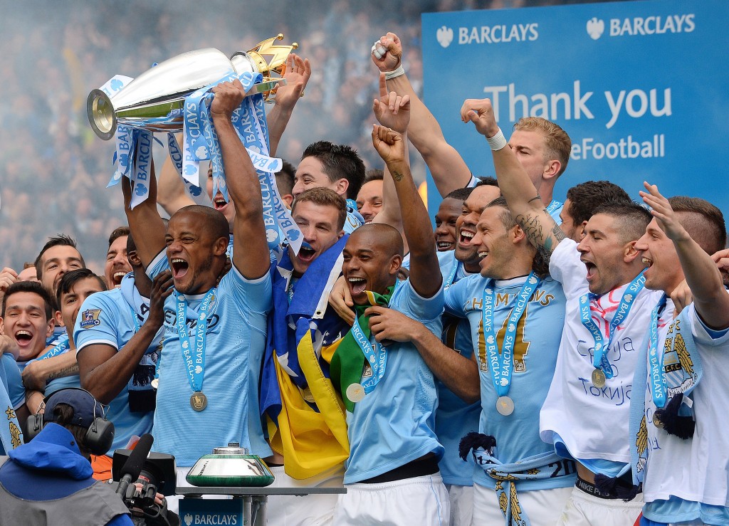 Manchester City's Belgian midfielder Vincent Kompany celebrates with the trophy after his team won the Premiership title following their victory in the English Premier League football match between Manchester City and West Ham United at the Etihad Stadium in Manchester on May 11, 2014. AFP PHOTO/ANDREW YATES RESTRICTED TO EDITORIAL USE. No use with unauthorized audio, video, data, fixture lists, club/league logos or live services. Online in-match use limited to 45 images, no video emulation. No use in betting, games or single club/league/player publications. (Photo credit should read ANDREW YATES/AFP/Getty Images)