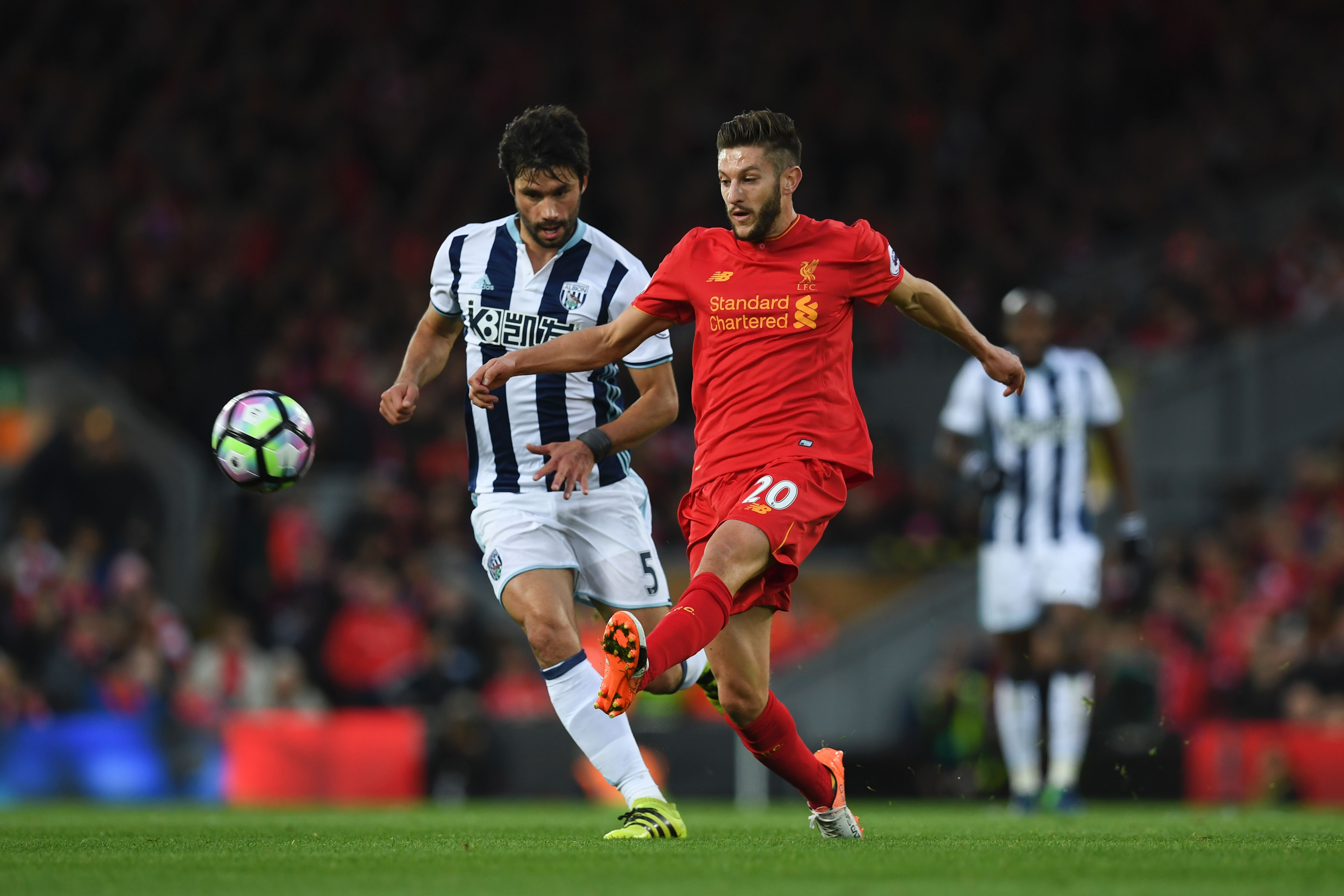 Liverpool's English midfielder Adam Lallana (R) plays the ball ahead of West Bromwich Albion's Argentinian midfielder Claudio Yacob (L) during the English Premier League football match between Liverpool and West Bromwich Albion at Anfield in Liverpool, north west England on October 22, 2016. / AFP / PAUL ELLIS / RESTRICTED TO EDITORIAL USE. No use with unauthorized audio, video, data, fixture lists, club/league logos or 'live' services. Online in-match use limited to 75 images, no video emulation. No use in betting, games or single club/league/player publications. / (Photo credit should read PAUL ELLIS/AFP/Getty Images)