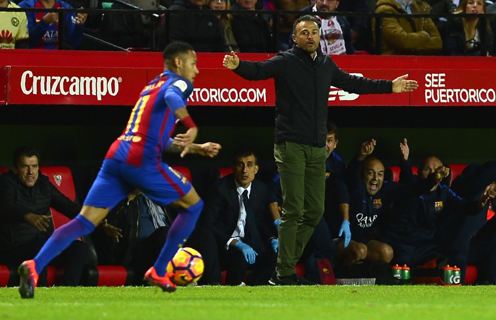Barcelona's coach Luis Enrique (back) as Barcelona's Brazilian forward Neymar drives the ball during the Spanish league football match Sevilla FC vs FC Barcelona at the Ramon Sanchez Pizjuan stadium in Sevilla on November 6, 2016. / AFP / CRISTINA QUICLER (Photo credit should read CRISTINA QUICLER/AFP/Getty Images)
