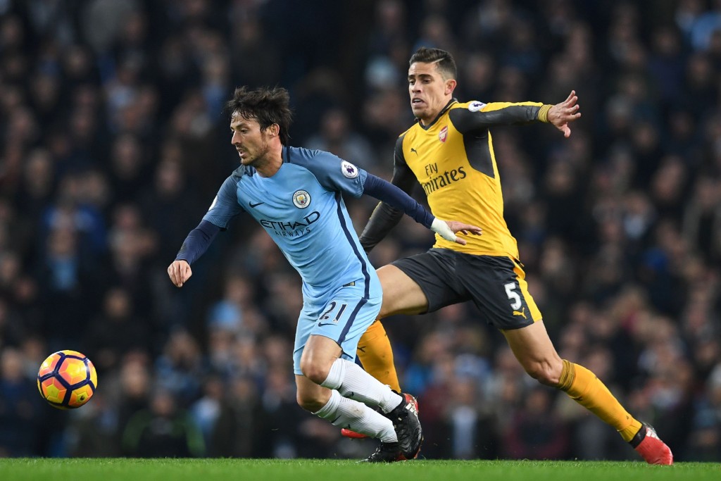 Manchester City's Spanish midfielder David Silva (L) vies with Arsenal's Brazilian defender Gabriel during the English Premier League football match between Manchester City and Arsenal at the Etihad Stadium in Manchester, north west England, on December 18, 2016. / AFP / Paul ELLIS / RESTRICTED TO EDITORIAL USE. No use with unauthorized audio, video, data, fixture lists, club/league logos or 'live' services. Online in-match use limited to 75 images, no video emulation. No use in betting, games or single club/league/player publications. / (Photo credit should read PAUL ELLIS/AFP/Getty Images)