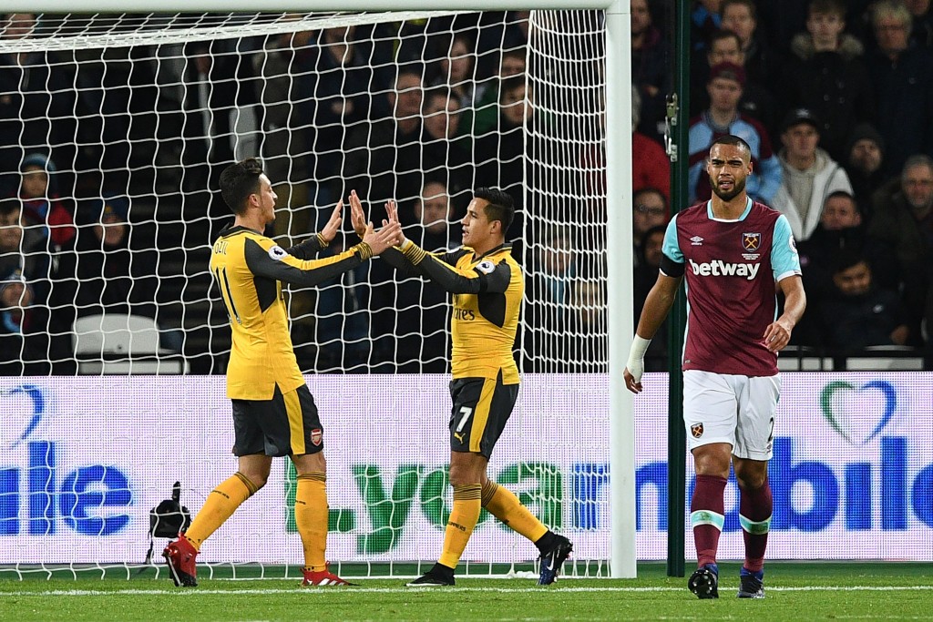 Arsenal's German midfielder Mesut Ozil (L) celebrates with Arsenal's Chilean striker Alexis Sanchez after scoring the opening goal of the English Premier League football match between West Ham United and Arsenal at The London Stadium, in east London on December 3, 2016. / AFP / Justin TALLIS / RESTRICTED TO EDITORIAL USE. No use with unauthorized audio, video, data, fixture lists, club/league logos or 'live' services. Online in-match use limited to 75 images, no video emulation. No use in betting, games or single club/league/player publications. / (Photo credit should read JUSTIN TALLIS/AFP/Getty Images)