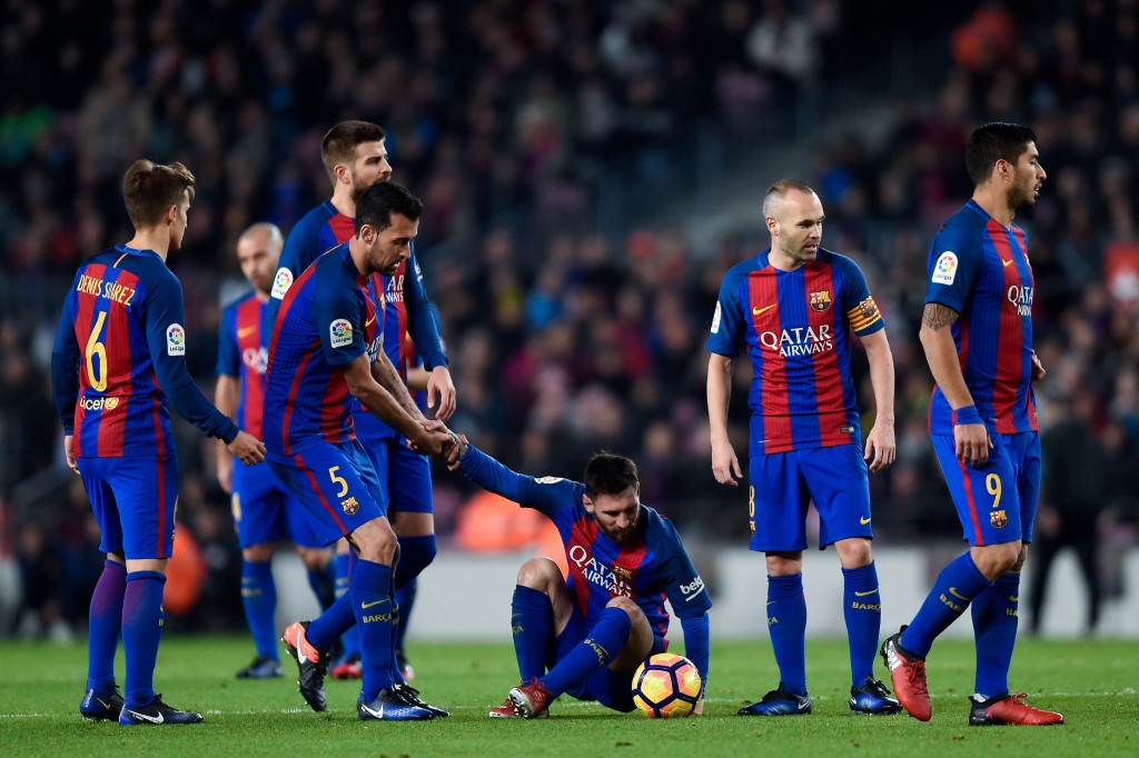 BARCELONA, SPAIN - DECEMBER 18: Sergio Busquets of FC Barcelona helps his team mate Lionel Messi during the La Liga match between FC Barcelona and RCD Espanyol at the Camp Nou stadium on December 18, 2016 in Barcelona, Spain. (Photo by David Ramos/Getty Images)