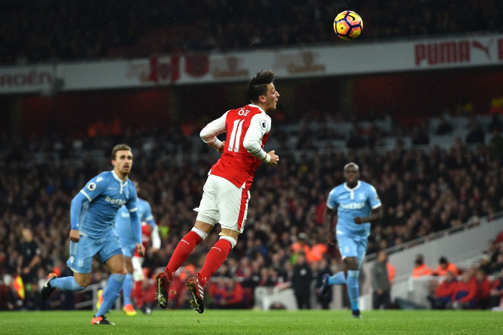 Arsenal's German midfielder Mesut Ozil (C) heads the ball to score their second goal during the English Premier League football match between Arsenal and Stoke City at the Emirates Stadium in London on December 10, 2016.  / AFP / Glyn KIRK / RESTRICTED TO EDITORIAL USE. No use with unauthorized audio, video, data, fixture lists, club/league logos or 'live' services. Online in-match use limited to 75 images, no video emulation. No use in betting, games or single club/league/player publications.  /         (Photo credit should read GLYN KIRK/AFP/Getty Images)