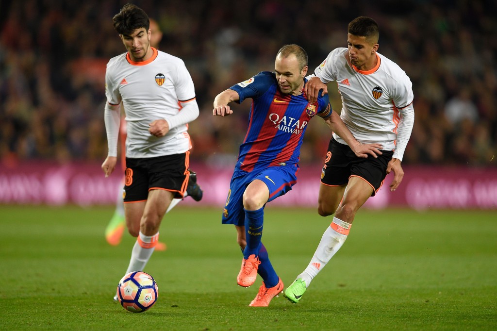 Barcelona's midfielder Andres Iniesta vies with Valencia's Portuguese defender Joao Cancelo (R) and Valencia's Argentinian midfielder Enzo Perez (L) during the Spanish league football match FC Barcelona vs Valencia CF at the Camp Nou stadium in Barcelona on March 19, 2017. / AFP PHOTO / LLUIS GENE (Photo credit should read LLUIS GENE/AFP/Getty Images)