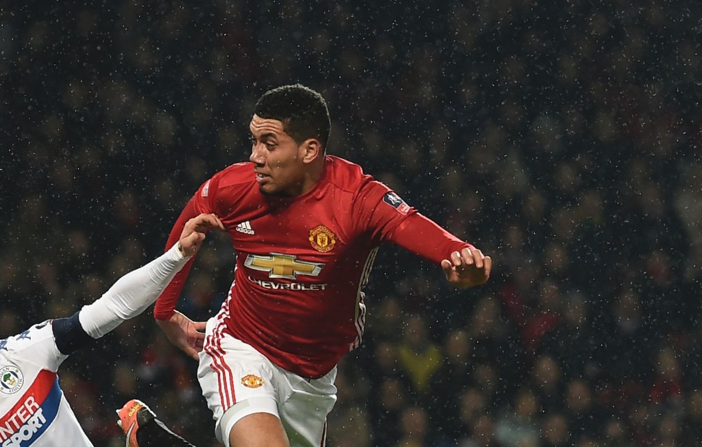 Manchester United's English defender Chris Smalling (R) heads the ball in to score their second goal during the English FA Cup fourth round football match between Manchester United and Wigan Athletic at Old Trafford in Manchester, north west England, on January 29, 2017. / AFP / Paul ELLIS / RESTRICTED TO EDITORIAL USE. No use with unauthorized audio, video, data, fixture lists, club/league logos or 'live' services. Online in-match use limited to 75 images, no video emulation. No use in betting, games or single club/league/player publications. / (Photo credit should read PAUL ELLIS/AFP/Getty Images)