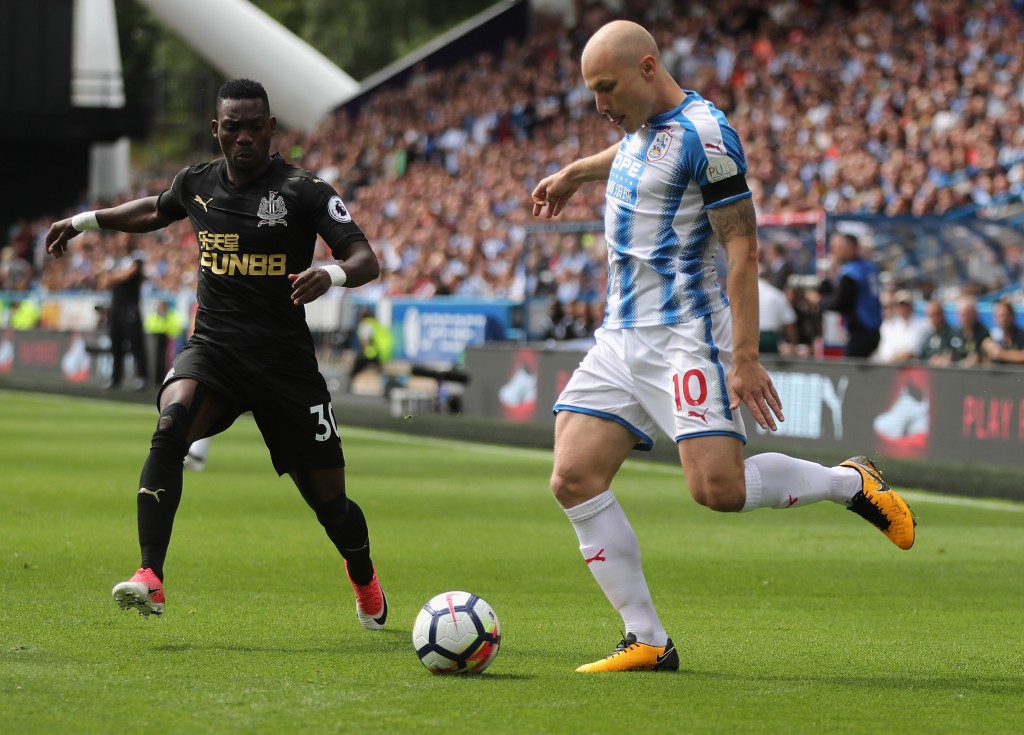 HUDDERSFIELD, ENGLAND - AUGUST 20: Aaron Mooy of Huddersfield Town passes the ball watched by Christian Atsu during the Premier League match between Huddersfield Town and Newcastle United at John Smith's Stadium on August 20, 2017 in Huddersfield, England. (Photo by David Rogers/Getty Images)
