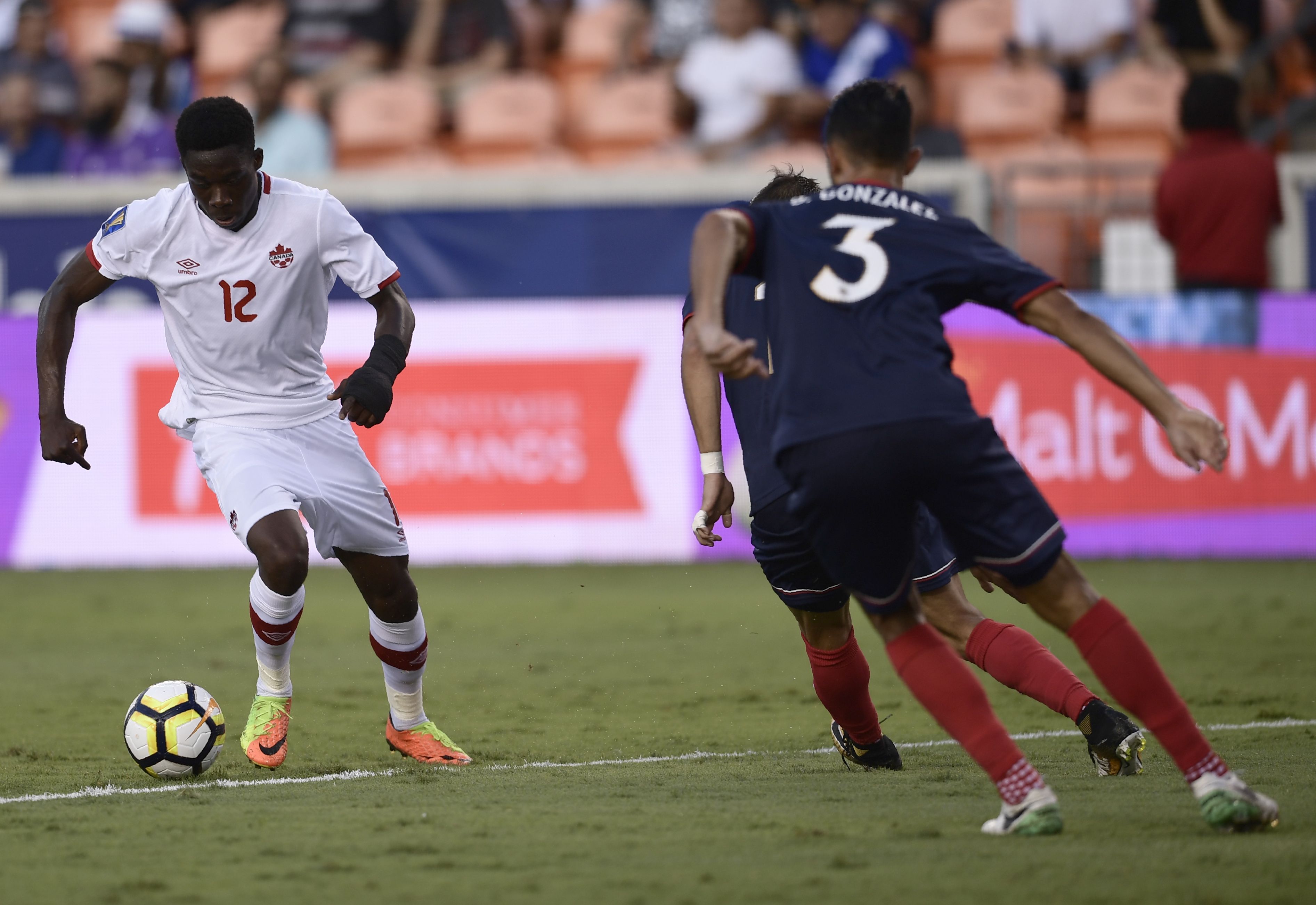 Canada's midfielder Alphonso Davies (L) kicks the ball during the Costa Rica vs. Canada 2017 CONCACAF Gold Cup match at the BBVA Compass Stadium July 11, 2017 in Houston, Texas. / AFP PHOTO / Brendan Smialowski (Photo credit should read BRENDAN SMIALOWSKI/AFP/Getty Images)