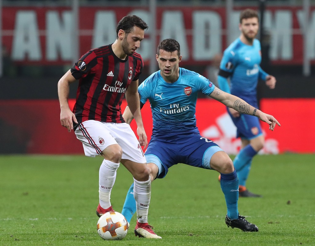 MILAN, ITALY - MARCH 08: Hakan Calhanoglu of AC Milan competes for the ball withGranit Xhaka of Arsenal during UEFA Europa League Round of 16 match between AC Milan and Arsenal at the San Siro on March 8, 2018 in Milan, Italy. (Photo by Marco Luzzani/Getty Images)
